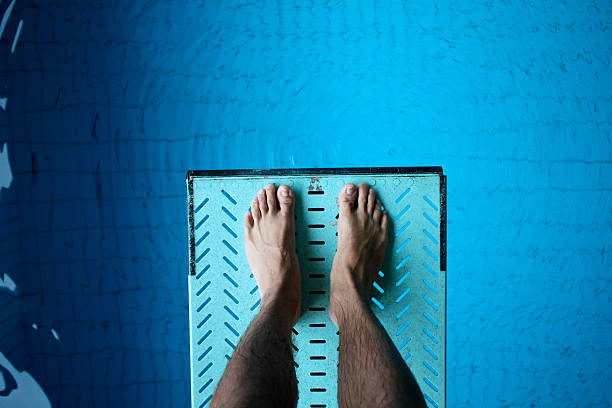 feet on diving board over pool stock photo