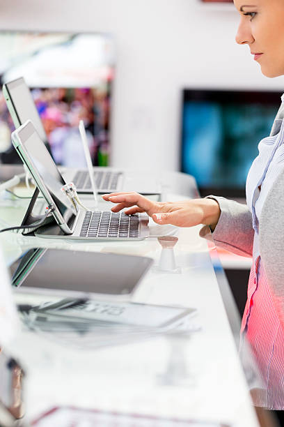 Buying laptop Woman buying laptop in electronics store, typing on computer keyboard computer shop stock pictures, royalty-free photos & images