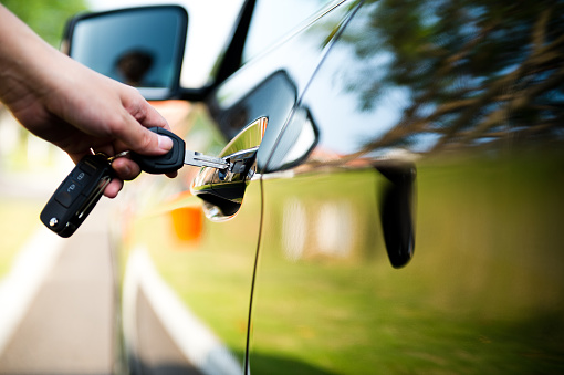 Woman putting key in car door.