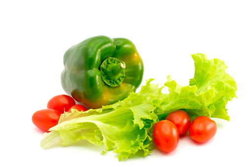 Wet lettuce with green pepper and many cherry tomatoes isolated on white background