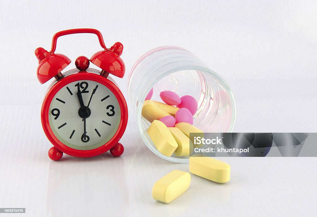 Red clock and tablet in glass on white background Red clock and tablet in glass on white background show medicine time Backgrounds Stock Photo