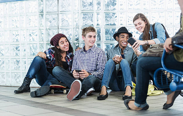 istock Multiracial teenagers sitting on floor in train station, texting 483576565