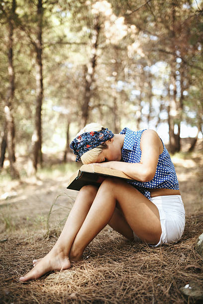 istock Young woman reading book in nature 483579606