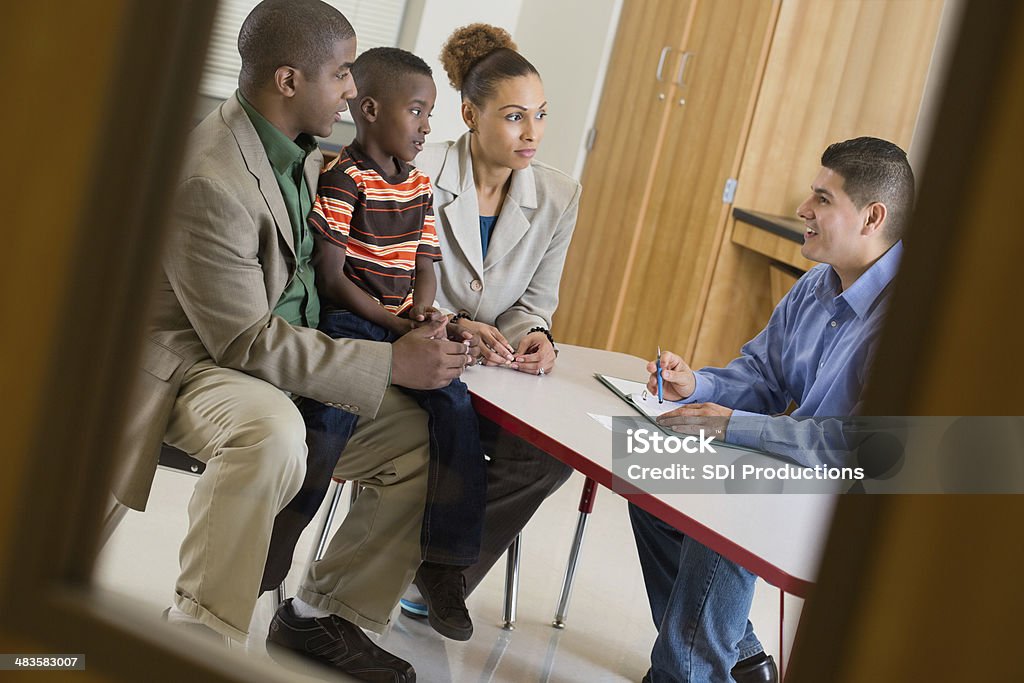 Padre con hijo de la reunión sobre el comportamiento con el maestro en la escuela - Foto de stock de Dia de los padres en el colegio libre de derechos