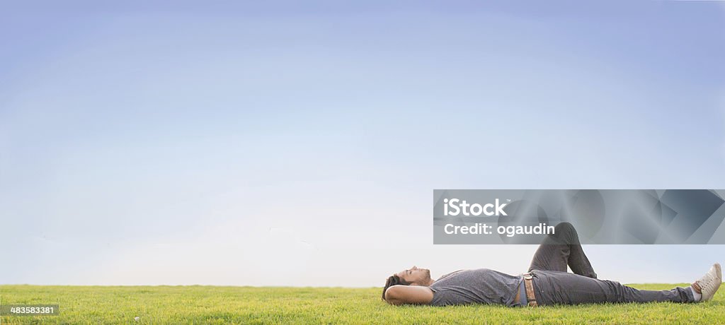 Relax Relaxed young man laying on grass. Blue sky Lying Down Stock Photo