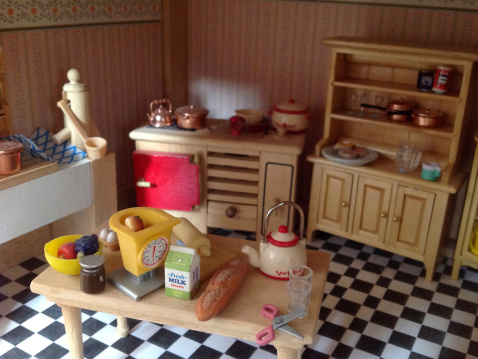 Frome, Somerset, England,UK - 19, March 2014: Photograph of an interior of a large wooden dolls house kitchen (Victorian style), with furnishings such as a cooker, sink, cabinets, plastic food and tiled flooring.