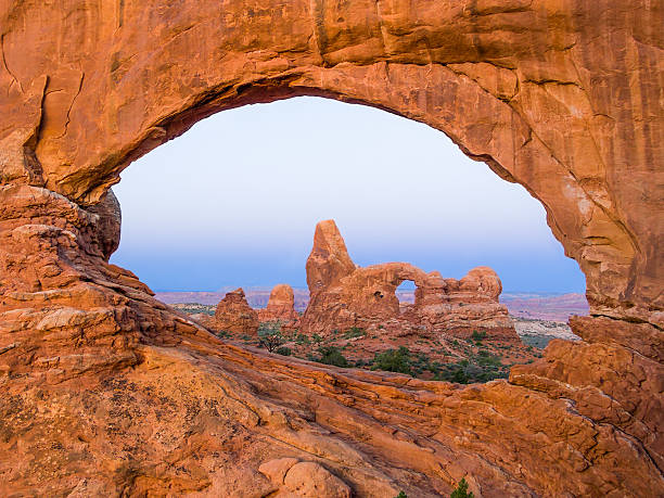 Turret Arch through North Window The Turret Arch is viewed through another arch, the North Window, at Arches National Park near Moab, Utah just before sunrise. slickrock trail stock pictures, royalty-free photos & images