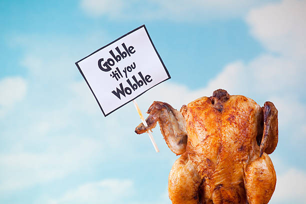 Thanksgiving turkey holding sign A roasted turkey holding a sign that reads "gobble til you wobble". turkey meat photos stock pictures, royalty-free photos & images