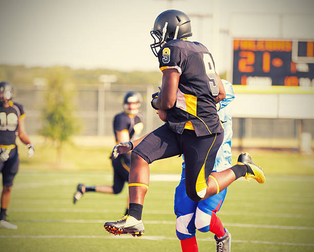 semi pro jogador de futebol de saltar para pegar bola duirng jogo - football player group of people running american football - fotografias e filmes do acervo