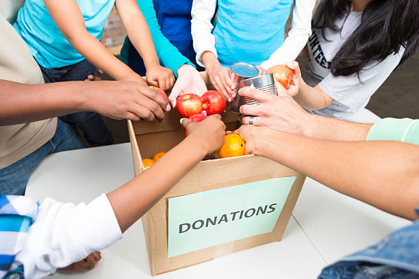 diverse volontari di effettuare donazioni di cibo in scatola in banca - food motivation driving drive foto e immagini stock