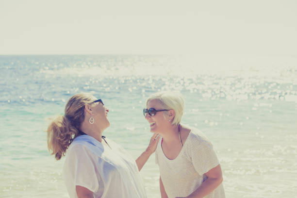 Two young women sharing a happy embrace on a sandy beach, radiating friendship and joy.