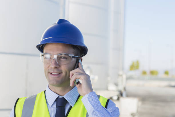istock Close up of worker talking on cell phone in front of silage storage tower 483596495