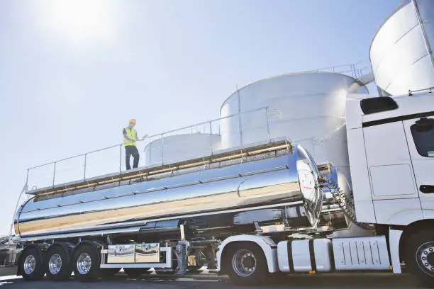 Photo of Worker on platform above stainless still milk tanker