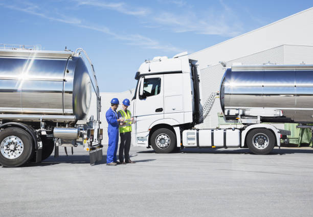 Workers talking next to stainless steel milk tankers  fuel tanker stock pictures, royalty-free photos & images