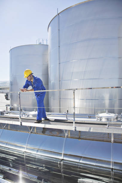 istock Worker using cell phone on platform above stainless steel milk tanker 483596671