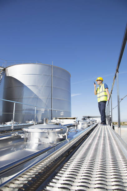 istock Worker using walkie-talkie on platform above stainless still milk tanker 483596703