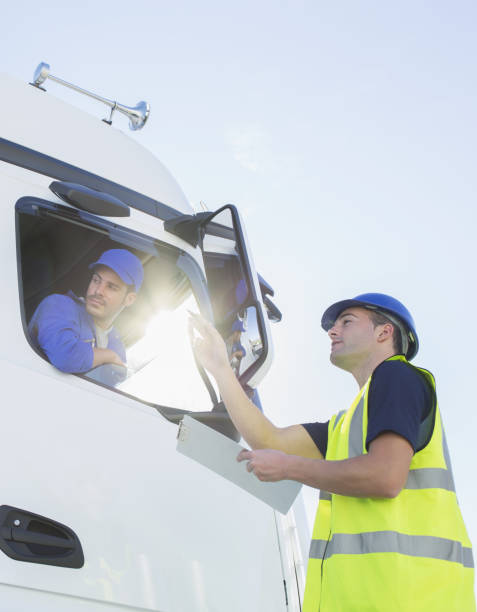 istock Worker with clipboard directing truck driver 483596823