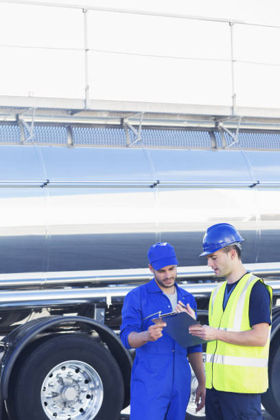 istock Workers with clipboard talking next to stainless steel milk tanker 483596829
