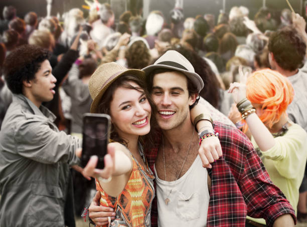 Couple taking self-portrait at music festival  festival goer stock pictures, royalty-free photos & images