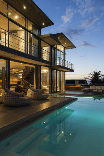 Luxury Villa Exterior At Night With Swimming Pool, Sofa And Lounge Chairs.