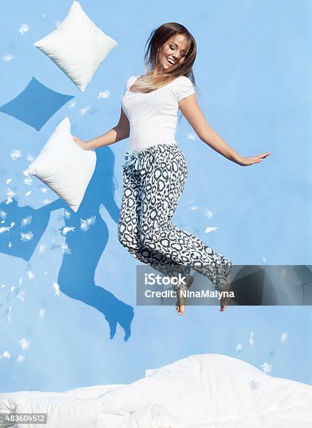 Young Woman Holding A Pillow Jumping Up On Bed Stock Photo - Download Image Now - Bed - Furniture, Flying, Fun