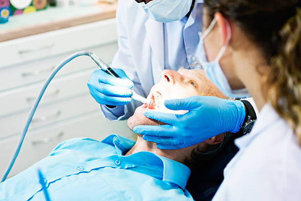 istock Dentist drilling a patient's teeth, dental nurse looking on 483606656