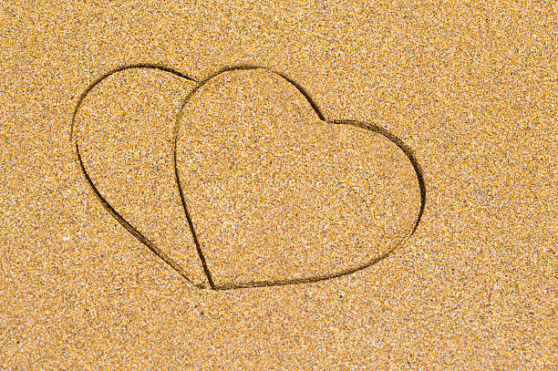 istock Two heart shape engraved in a wet sandy beach 483607912
