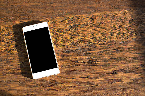 istock White phone on a wooden table. close-up 483609224