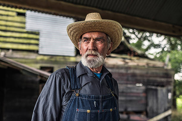 istock Old farmer standing in front of a rustic barn 483611844