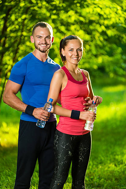 Homme et Femme buvant à la bouteille d'eau après fitness sport - Photo