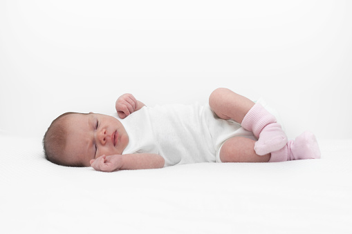 Adorable newborn baby girl is napping on white blanket