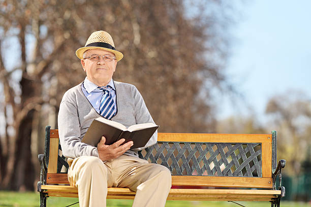istock Elderly gentleman with book posing on a bench 483616863