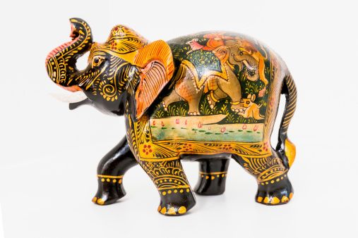 Colorful handmade and hand painted wooden elephant souvenir on white background.