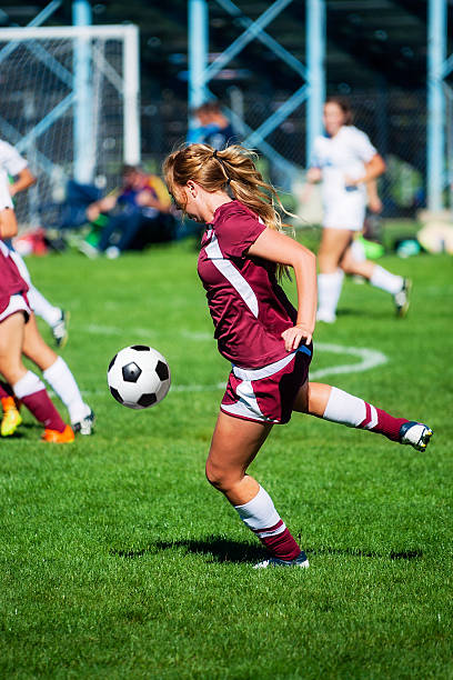 Attractive Female Soccer Player Concentrates on Airborne Ball A royalty free DSLR action photo of an attractive female soccer player eyes airborne ball. This image was captured under actual game conditions reflecting competitive intensity. high school soccer stock pictures, royalty-free photos & images