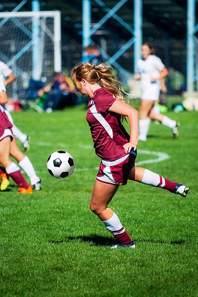 Attractive Female Soccer Player Concentrates on Airborne Ball A royalty free DSLR action photo of an attractive female soccer player eyes airborne ball. This image was captured under actual game conditions reflecting competitive intensity. offense sporting position stock pictures, royalty-free photos & images