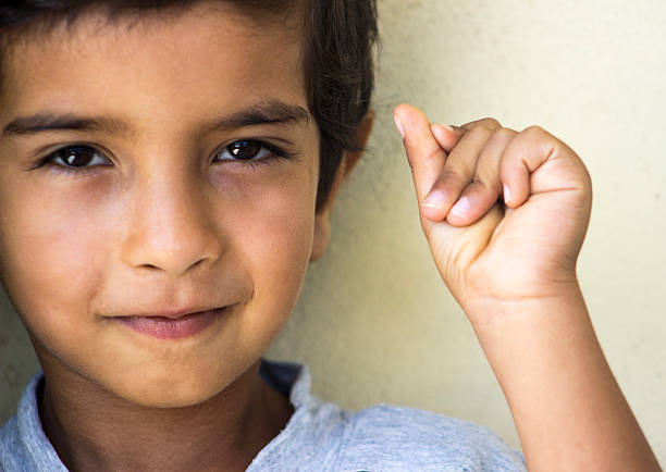 Cute little boy raising his hand over white background