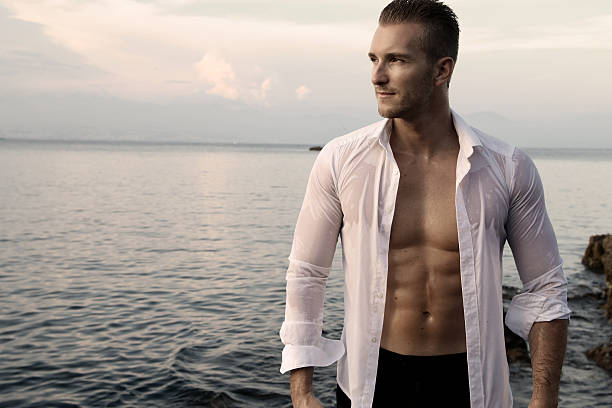 Sexy man wearing an open shirt handsome man wearing an open shirt facing the sea sex symbol stock pictures, royalty-free photos & images