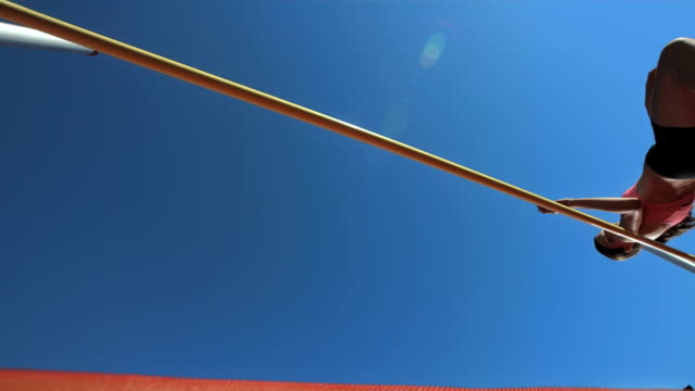 HD Super Slow-Mo: Female Athlete Jumping Over A Horizontal Bar