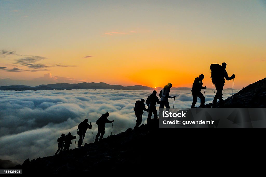 Silhouettes of hikers At Sunset Silhouettes of hikers climbing the mountain at sunset. Mountain Climbing Stock Photo