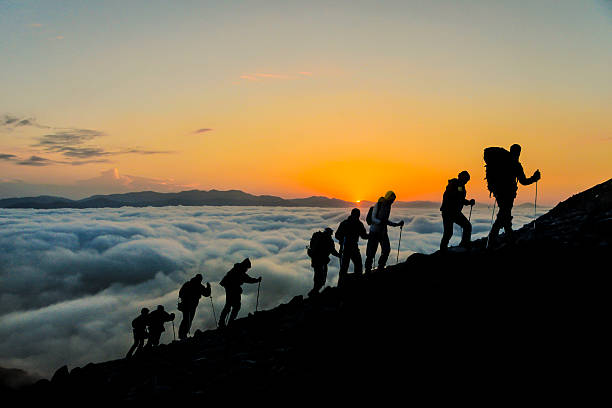 Silhouettes of hikers At Sunset Silhouettes of hikers climbing the mountain at sunset. rock climbing stock pictures, royalty-free photos & images