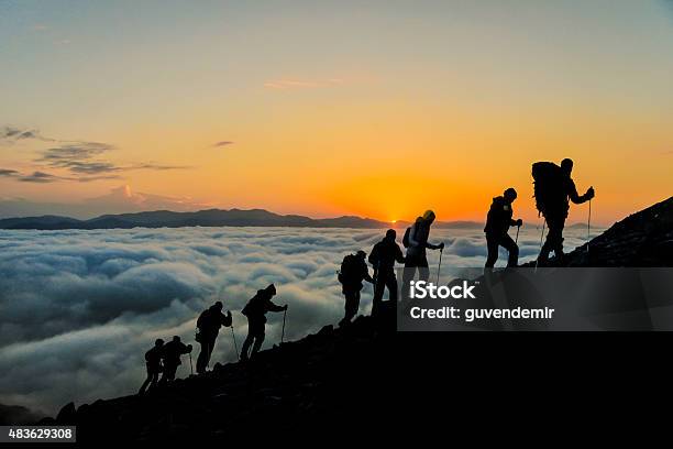 Silhouettes Of Hikers At Sunset Stock Photo - Download Image Now - Mountain Climbing, Teamwork, Sports Team