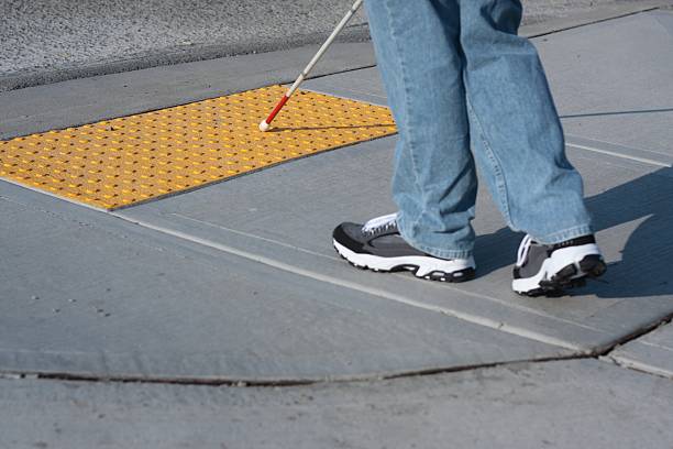 Accessible Sidewalk Edge - Selective Focus Bumps ("truncated domes") at the edge of a crosswalk tell a blind cane user that he is about to step out into the street.  Selective focus - cane tip is in focus, shoes and sidwalk are slightly out of focus. blind persons cane stock pictures, royalty-free photos & images