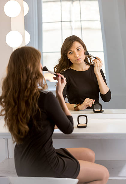 istock young elegant woman doing makeup at mirror with bulbs 483630016