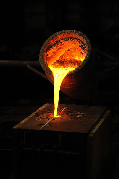 Foundry - molten metal poured from ladle into mould Foundry - molten metal poured from ladle into mould - lost wax casting power equipment stock pictures, royalty-free photos & images