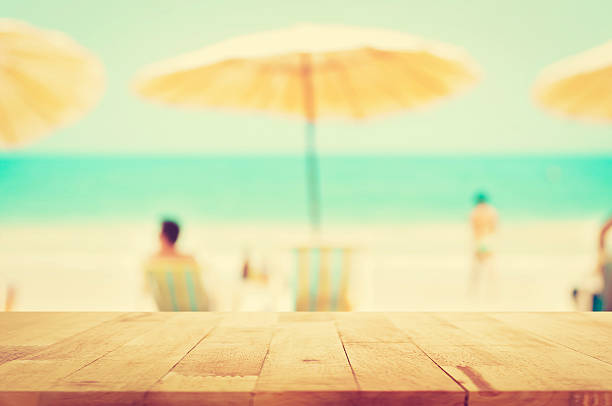 istock Wood table top on blurred summer beach background with people 483631556