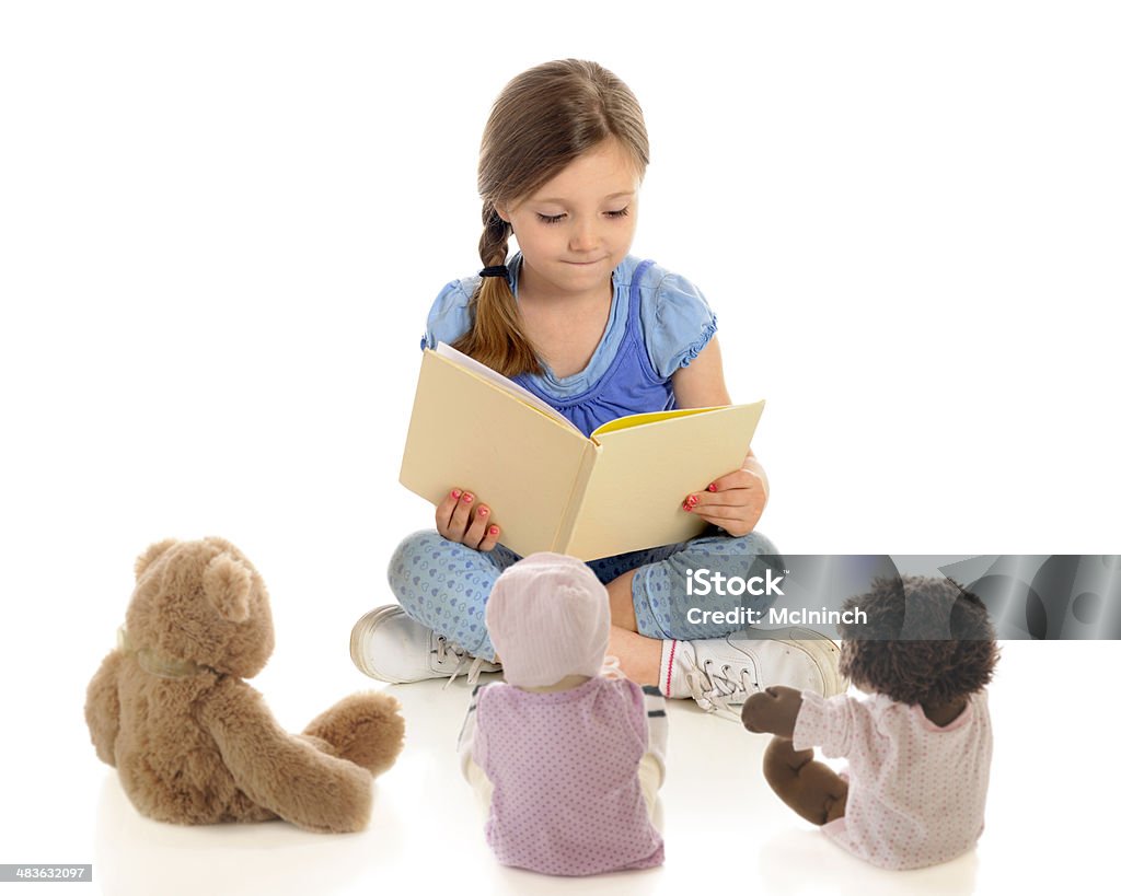 Young Reader, Tiny Listeners An adorable young "teacher" reading a book to her toy students.  On a white background. Child Stock Photo