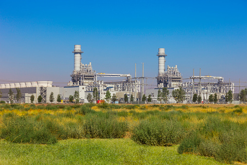 Natural gas fired turbine power plant with it's cooling towers rising into a blue sky