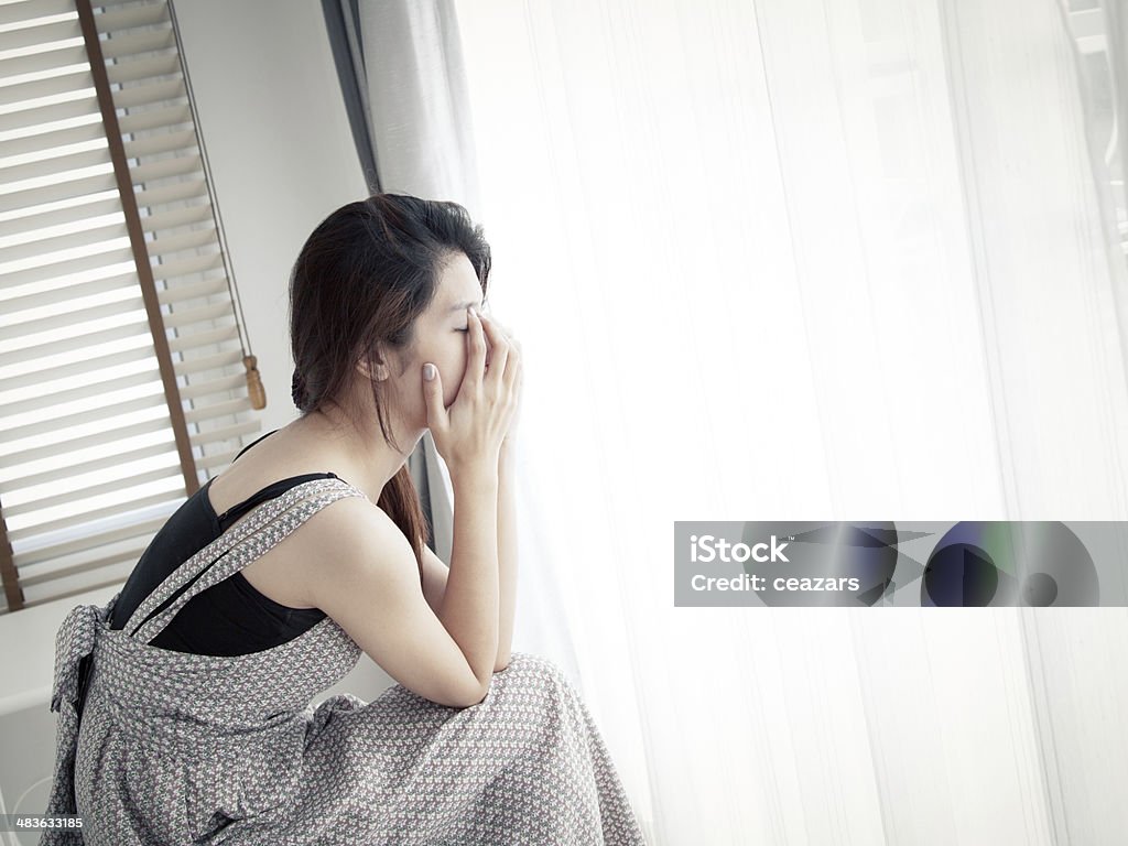 sad woman sitting alone in room Adolescence Stock Photo