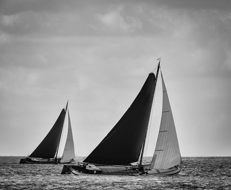 Classic Skutsje sailboats sailing on empty waters in black and white.