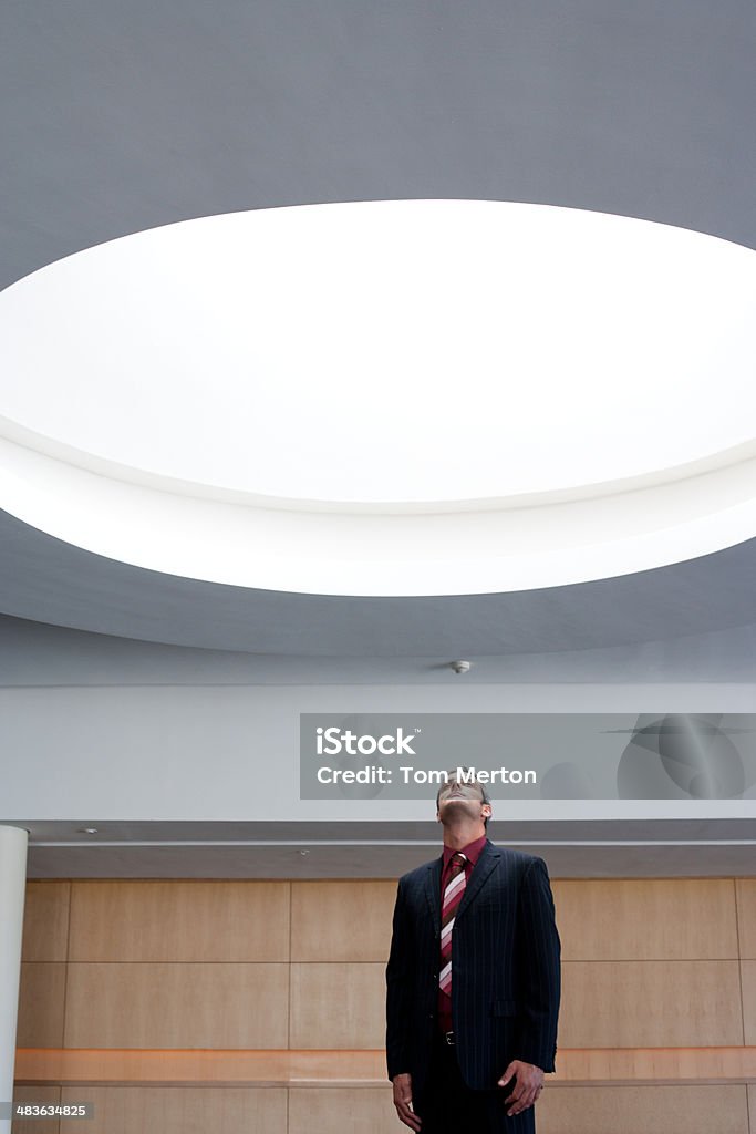 Businessman looking up at ceiling light  20-29 Years Stock Photo